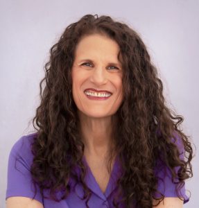 Meryl is a white female with long brown curly hair and a lavender top.