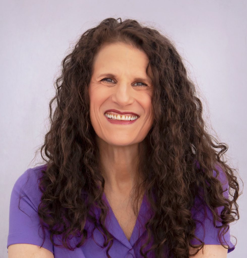 Meryl is a white female with long brown curly hair and a lavender top.